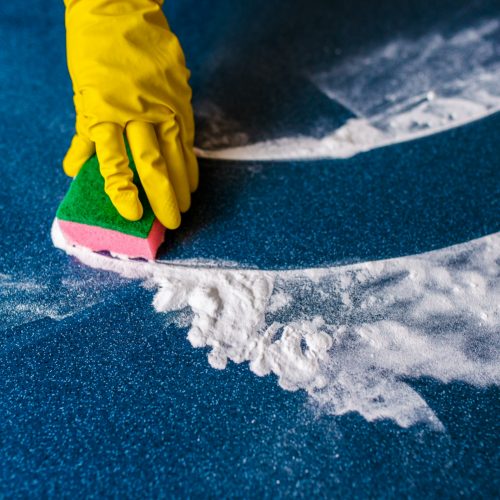 esponjas-coloridas-para-a-limpeza-em-um-fundo-azul-e-maos-amarelas-nas-luvas