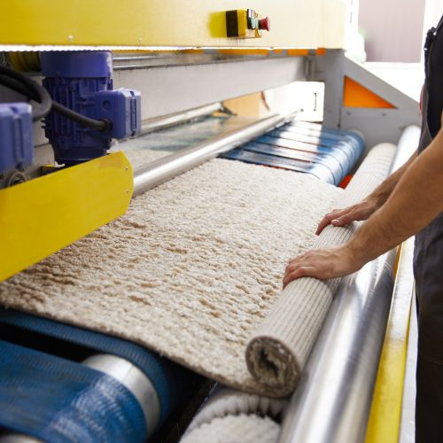 trabalhador-masculino-limpando-carpete-em-equipamento-de-maquina-de-lavar-e-secar-roupa-automatica-na-lavanderia